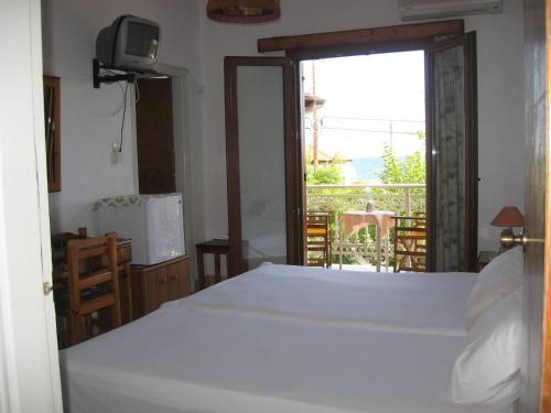 a bedroom with a white bed and a balcony at Marialena Pension in Iraion
