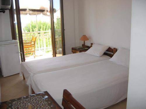 a bedroom with two beds and a balcony with a chair at Marialena Pension in Iraion