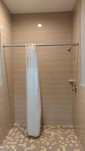 a shower with a white shower curtain in a bathroom at Haven Inn & Suites Downtown Houston. in Houston