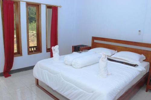 a bedroom with a bed with white sheets and pillows at Danke Lodge in Labuan Bajo