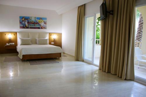 The Ksar Djerba Charming Hotel & SPA في ميدون: غرفة نوم بسرير ونافذة كبيرة