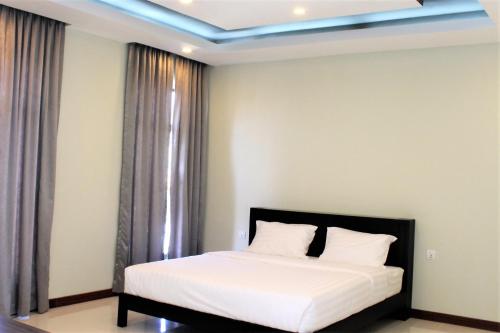 a bedroom with a bed with white sheets at Malis the Residence in Phnom Penh