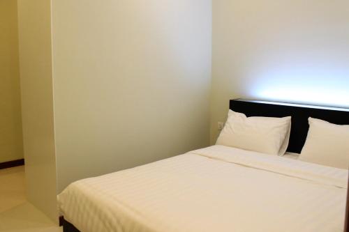 a bedroom with a white bed with a black headboard at Malis the Residence in Phnom Penh