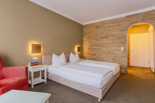 a bedroom with a large bed and a red chair at Hotel - Restaurant Erich Rödiger in Bad Staffelstein