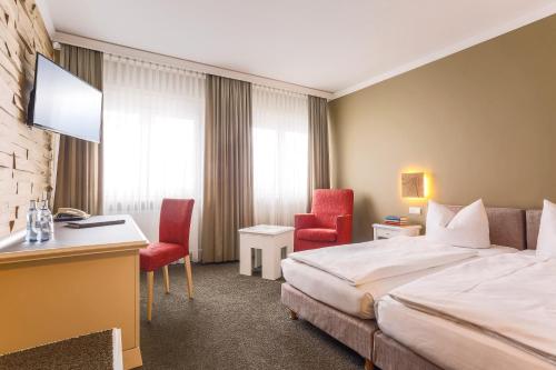 a hotel room with a bed and a desk and chairs at Hotel - Restaurant Erich Rödiger in Bad Staffelstein