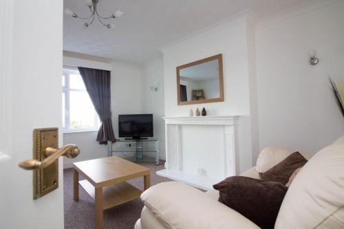 a living room with a white couch and a fireplace at Lovely Sea Front House in Cleethorpes on Beachfront sleeps up-to 6 in Cleethorpes
