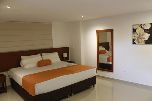 a bedroom with a large bed and a mirror at Hotel Bachue in Barrancabermeja