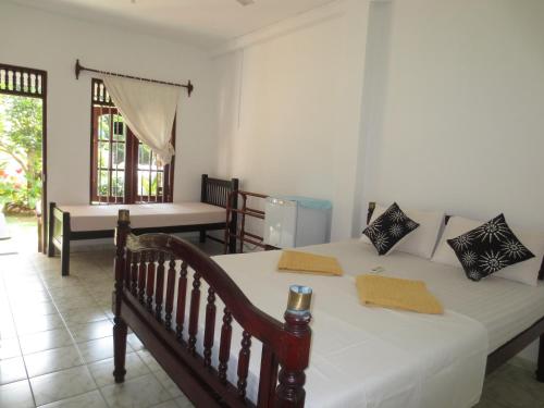 a bedroom with two beds and a table and a window at Jungle Holiday Home in Hikkaduwa