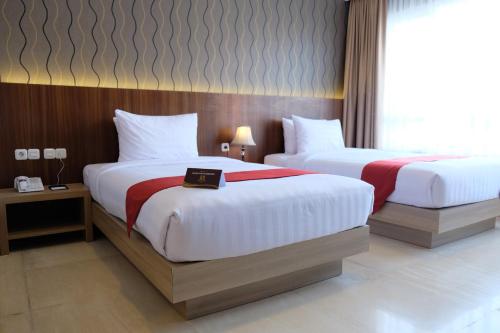 een hotelkamer met twee bedden en een boek erop bij Mexolie Hotel in Kebumen