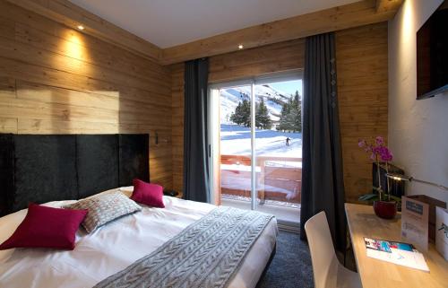 a bedroom with a bed and a large window at Hotel Les Mélèzes in Les Deux Alpes