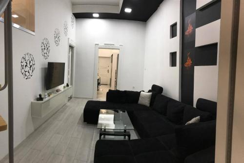 デブレツェンにあるManyi Apartmanのリビングルーム(黒いソファ、テレビ付)