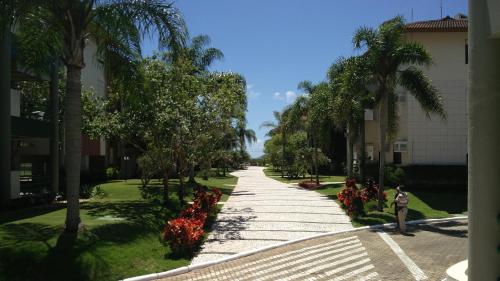 a person standing on a sidewalk next to a road with palm trees at Apto Cond. Porto Ventura 3 quartos in Florianópolis