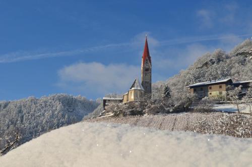 a church on a hill in the mountains with snow at Bachmannhof in Feldthurns
