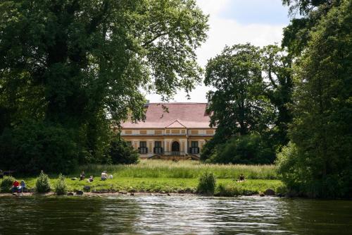 a large building with people sitting on the grass near a river at Ferienhaus Caputh in Caputh