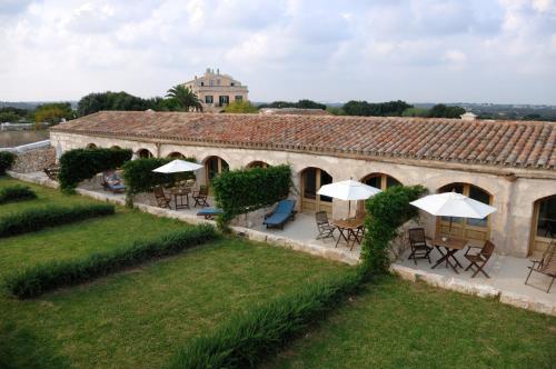 an old building with tables and umbrellas in a yard at Alcaufar Vell Hotel Rural & Restaurant in Sant Lluis