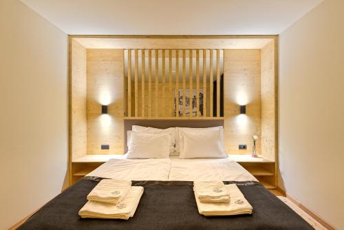 een slaapkamer met een groot bed en 2 handdoeken bij Apartments Budinek in Kranjska Gora