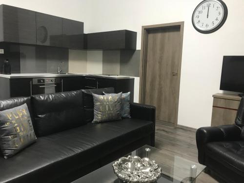a living room with a black leather couch and a clock at Old Town Boutique Apartments in Liberec