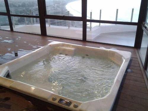a bath tub filled with water in front of a window at Jardin del Mar SPA & Enjoy in Coquimbo