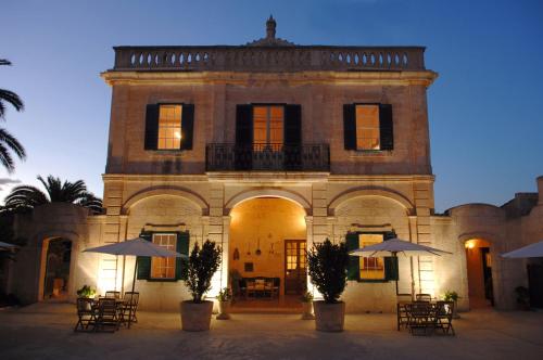 a building with tables and umbrellas in front of it at Alcaufar Vell Hotel Rural & Restaurant in Sant Lluis