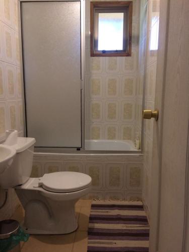ein Bad mit einem WC, einer Badewanne und einem Fenster in der Unterkunft Cabañas Pichares in Caburgua