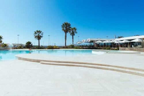 a large swimming pool with palm trees and a building at Jardin del Mar SPA & Enjoy in Coquimbo