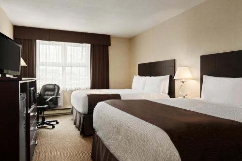 a hotel room with two beds and a flat screen tv at Days Inn by Wyndham Trois-Rivieres in Trois-Rivières