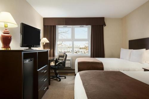 a hotel room with two beds and a television at Days Inn by Wyndham Trois-Rivieres in Trois-Rivières
