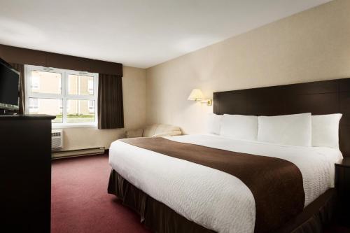 a hotel room with a large bed and a window at Days Inn by Wyndham Trois-Rivieres in Trois-Rivières