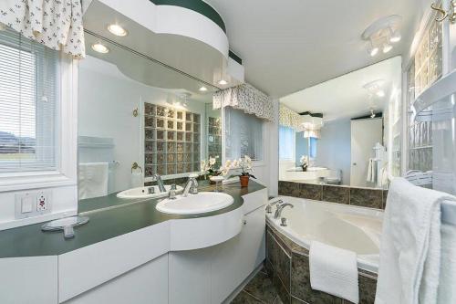 a white bathroom with two sinks and a tub at 271 - La Victorienne - Les Immeubles Charlevoix in Baie-Saint-Paul