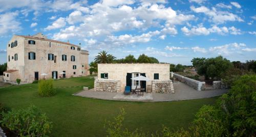 an external view of a large stone building with a yard at Alcaufar Vell Hotel Rural & Restaurant in Sant Lluis