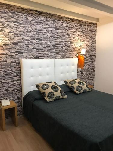 a bedroom with a bed with two pillows and a brick wall at Hotel Il Guercino in Bologna