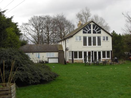 a large white house with a yard with green grass at The Brambles B&B in Waterbeach
