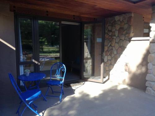 a patio with blue chairs and a table and glass doors at Conach House in Cambridge