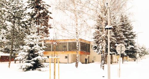 a building covered in snow in front of trees at Villa Green in Sliač