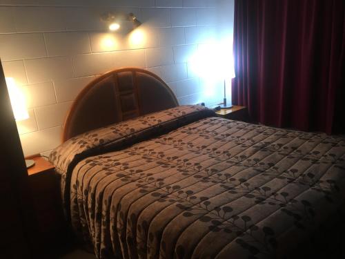 a bedroom with a bed with a blanket on it at New Haven Motel in Auckland