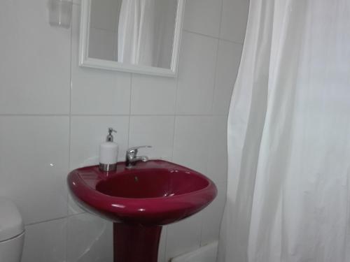 a bathroom with a red sink and a mirror at Hostal Tunquelen in Valparaíso