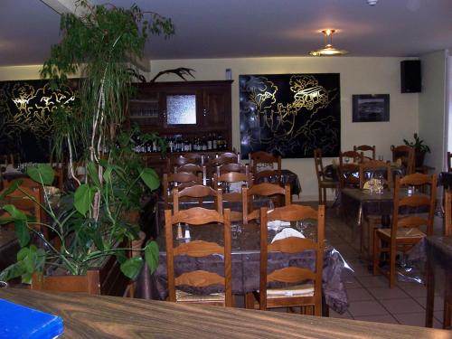 a dining room with tables and chairs and plants at La Vieille Auberge in Saint-Privat-dʼAllier