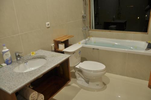 a bathroom with a toilet and a sink and a tub at Crystal Beach Bali in Candidasa