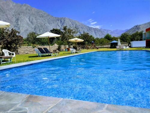 una gran piscina azul con sillas y sombrillas en Hotel Vallehermoso Lunahuana, en Lunahuaná