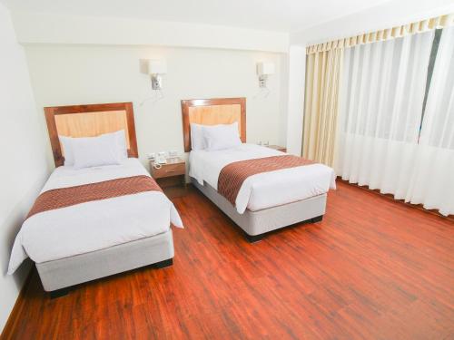 two beds in a hotel room with wood floors at Golden Sunrise Machupicchu in Machu Picchu