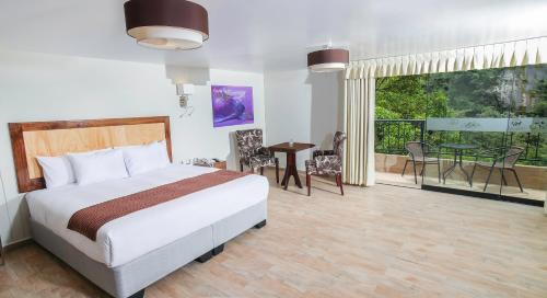 1 dormitorio con 1 cama y balcón con mesa en Golden Sunrise Machupicchu, en Machu Picchu