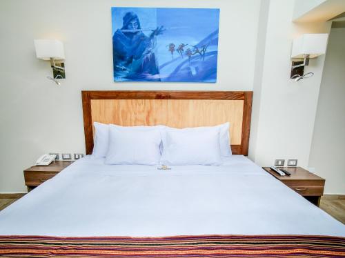 a bedroom with a large white bed with two night stands at Golden Sunrise Machupicchu in Machu Picchu