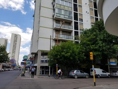 a man riding a bike in front of a tall building at M&A Apartamentos Temporales in Bahía Blanca