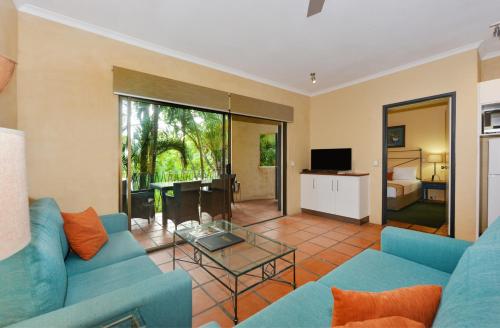 a living room with a blue couch and a glass table at Seascape Apartments at Villa San Michele in Port Douglas