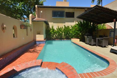 a swimming pool in a yard with a house at Seascape Apartments at Villa San Michele in Port Douglas
