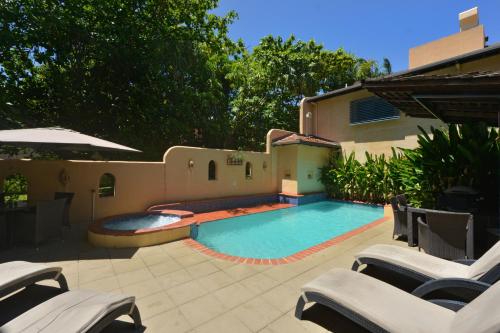 a swimming pool in a yard with chairs next to a house at Seascape Apartments at Villa San Michele in Port Douglas