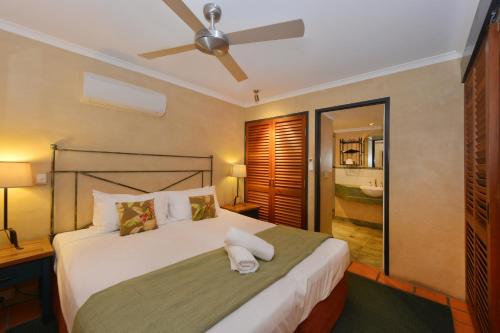 a bedroom with a large bed with a ceiling fan at Seascape Apartments at Villa San Michele in Port Douglas