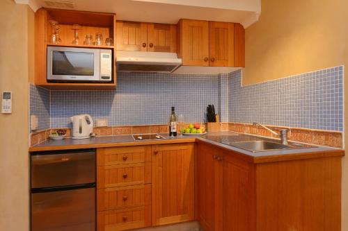 a kitchen with wooden cabinets and a sink and a microwave at Seascape Apartments at Villa San Michele in Port Douglas