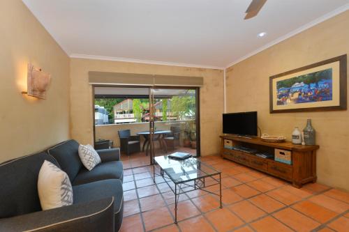 a living room with a couch and a tv at Seascape Apartments at Villa San Michele in Port Douglas