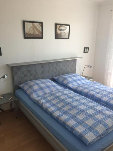 a bedroom with a bed with a blue plaid blanket at Nordlicht in Büsum-Stinteck in Stinteck